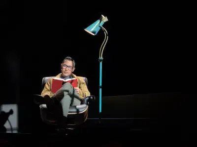 James (Marcus Choi) reads a book on stage before the show begins
